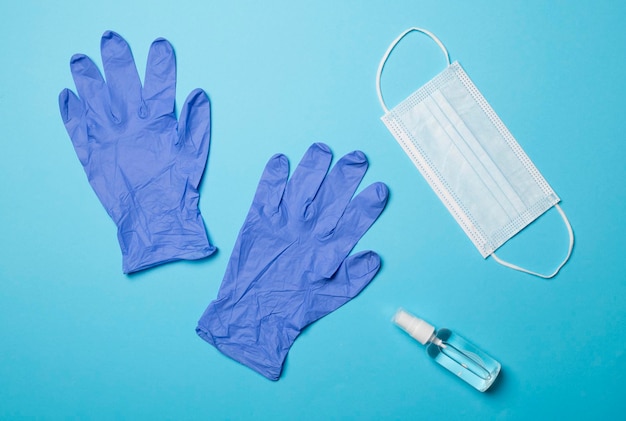 Latex gloves medical mask and hand sanitizer on color background Top view flat lay