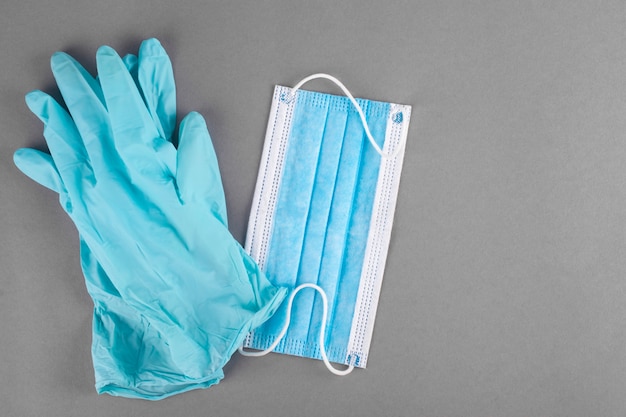 Latex medical gloves and mask on a gray background.