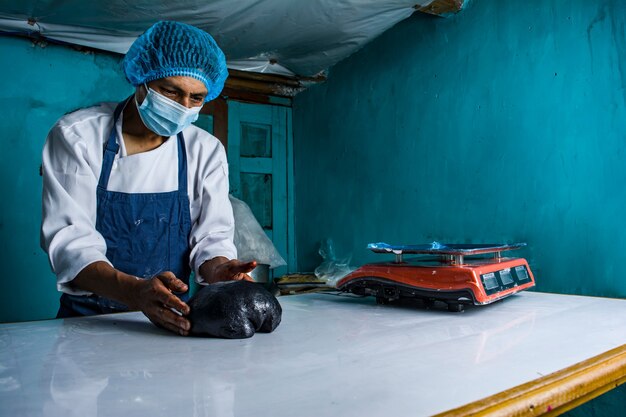 Lati baker preparing the dough and baking colored brioche breads and cookies in his humble bakery