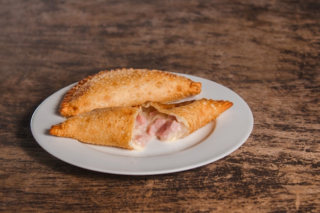 Foto latijns-amerikaanse gebakken ham en kaas empanadas die op een houten tafel.