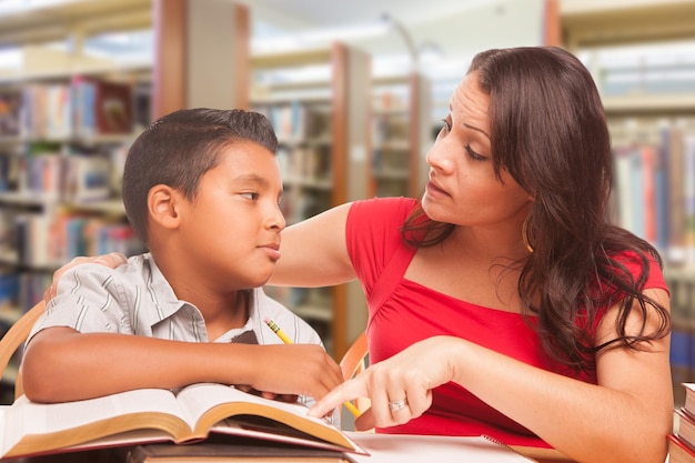 Latijns-Amerikaanse jongen en familie volwassenen die in de bibliotheek studeren