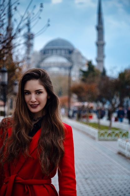 Latijns-Amerikaanse vrouw of Turkse vrouw in een rode stijlvolle jas voor de beroemde blauwe moskee in Istanbul