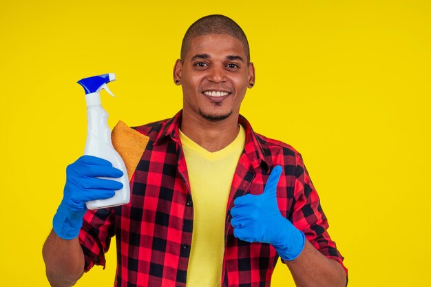 Latijns-Braziliaanse schoonmaak man met ribon handschoenen op studio gele achtergrond.