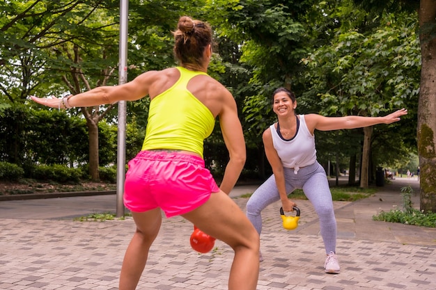 Latijns meisje dat sport doet in een park in de stad, een gezond leven leidt, twee meisjes die rekoefeningen doen en squats