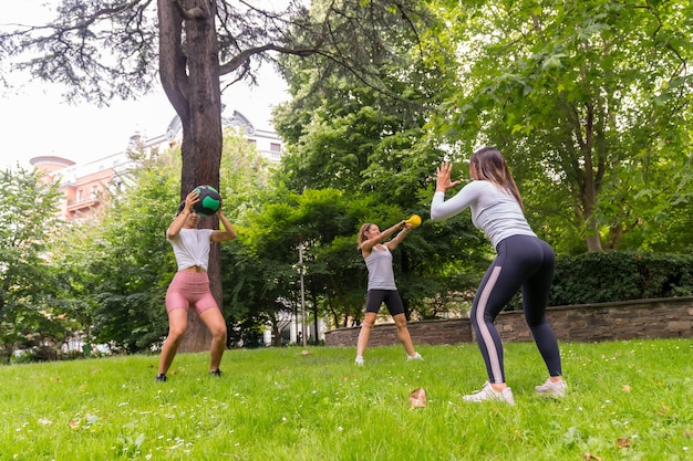 Latijns meisje doet oefeningen en sport in een groen park, instructeur die de studenten lesgeeft in een set gewichten