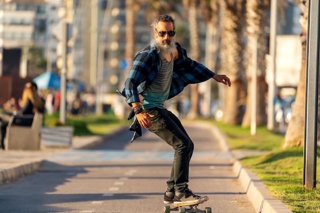 Latijnse baard senior man skateboard op fietspad en plezier in La Serenax