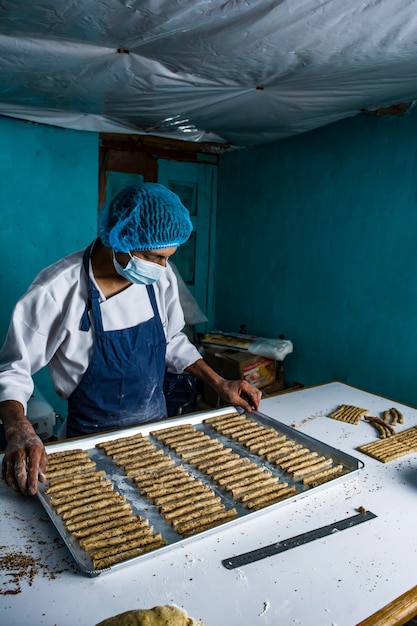 Latijnse bakker die het deeg klaarmaakt en gekleurde briochebroodjes en koekjes bakt