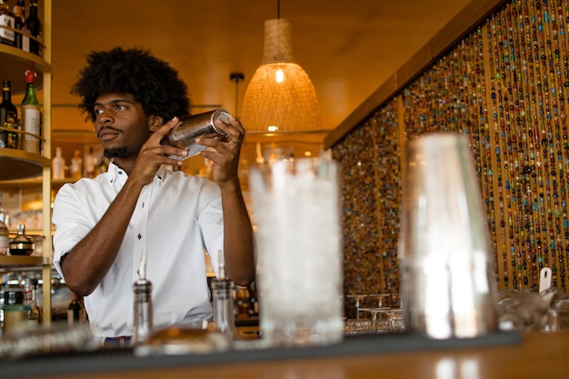 Latijnse barman met krullend haar dat alcohol schudt