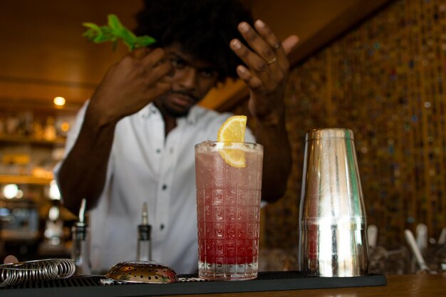 Latijnse barman met krullend haar die een cocktail beëindigt.