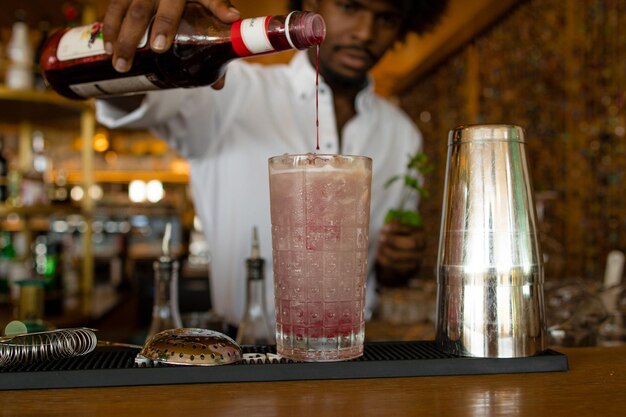 Latijnse barman met krullend haar die grenadine serveert