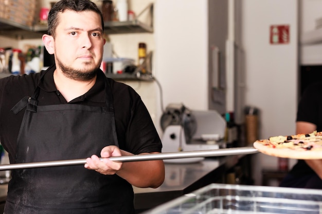 Latijnse chef-kok kook pizza in industriële professionele keuken oven venezolaans midden bakker