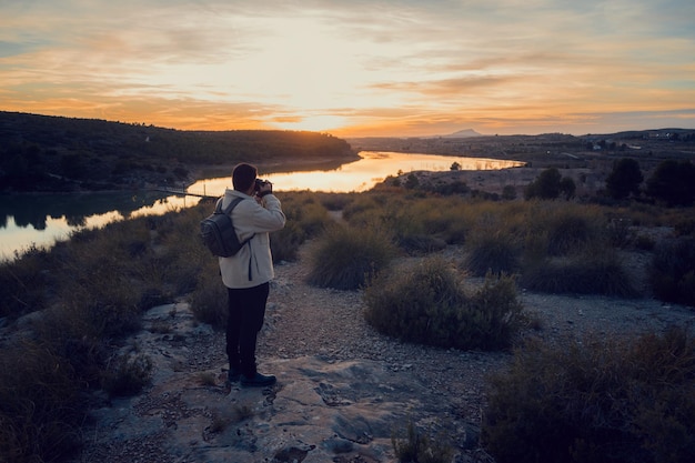 Latijnse fotograaf met een camera neemt foto's in een lagune bij zonsondergang