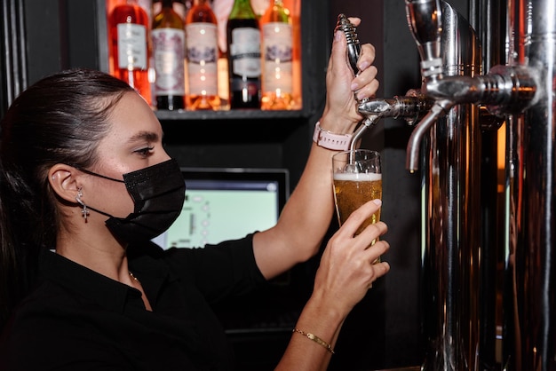 Latijnse jonge vrouw serveert een glas bier op een toog. werk serveerster beroep