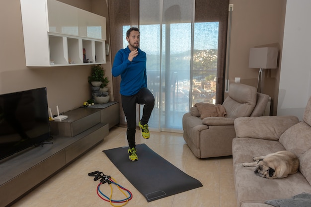 Latijnse man, aan het trainen in zijn woonkamer, doet sit-ups, rekoefeningen en squats