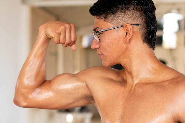 Latijnse man buigt zijn gespierde arm close-up foto van fitness man poseren en dragen van een bril