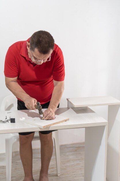 Foto latijnse man die spijkers hamert in meubelmontage