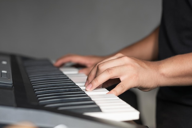 Latijnse man die synthesizer speelt, detailfoto van de handen van een jonge man die zijn liedjes oefent