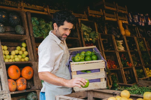 Latijnse man van middelbare leeftijd met een krat appels in een groentewinkel