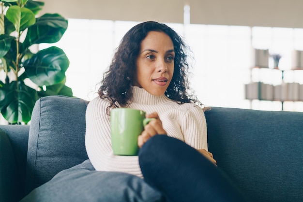 Latijnse vrouw die koffie drinkt op de bank