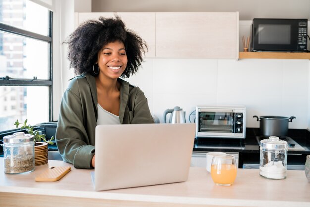 Latijnse vrouw die laptop thuis met behulp van.