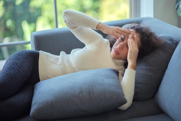 Latijnse vrouw die op de bank ligt met hoofdpijn.