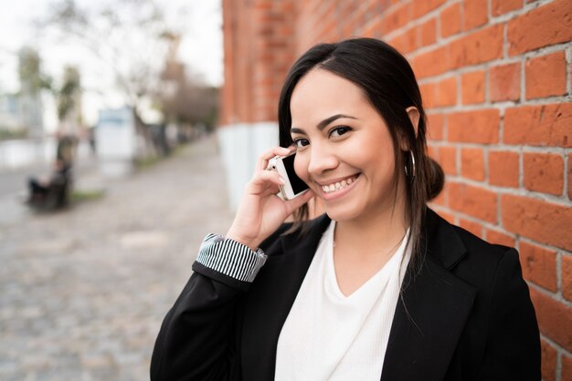 Latijnse vrouw die op de telefoon spreekt.