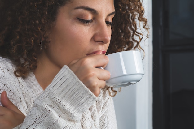 Latijnse vrouw die van kop van koffie geniet