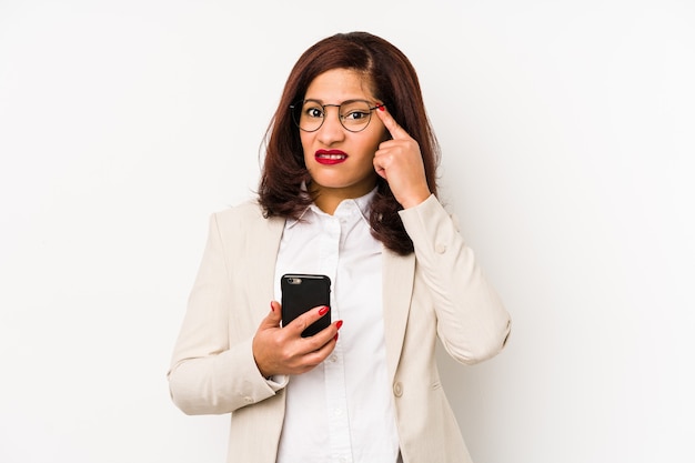 Latijnse vrouw die van middelbare leeftijd een mobiele telefoon houdt geïsoleerd met een teleurstelling gebaar met wijsvinger.