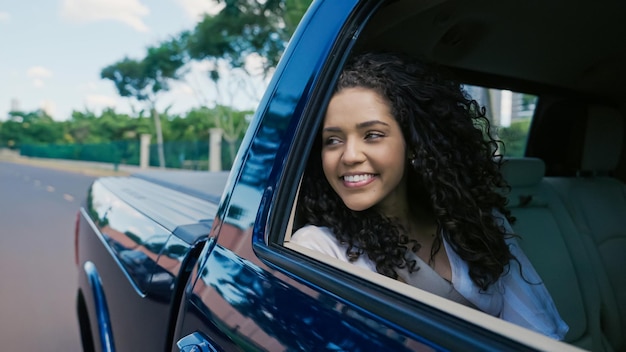 Latijnse vrouw in autoraam. Auto reis. Krullend haar in de wind. Meisje kijkt uit autoraam.