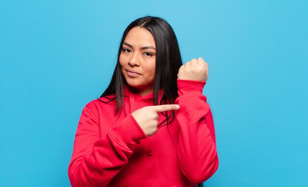 Latijnse vrouw kijkt ongeduldig en boos, wijst op horloge, vraagt om stiptheid, wil op tijd zijn