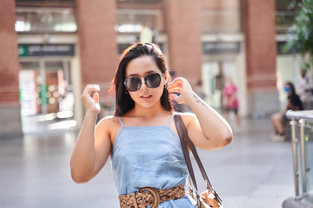 Latijnse vrouw met een zonnebril die modekleren draagt portret van een vrouw met stralende zonnestralen