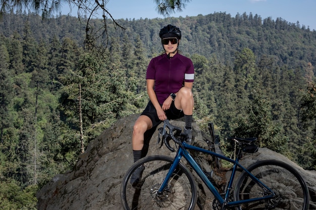 Latijnse vrouw met fiets rustend in het bos met een landschap van bomen op de achtergrond