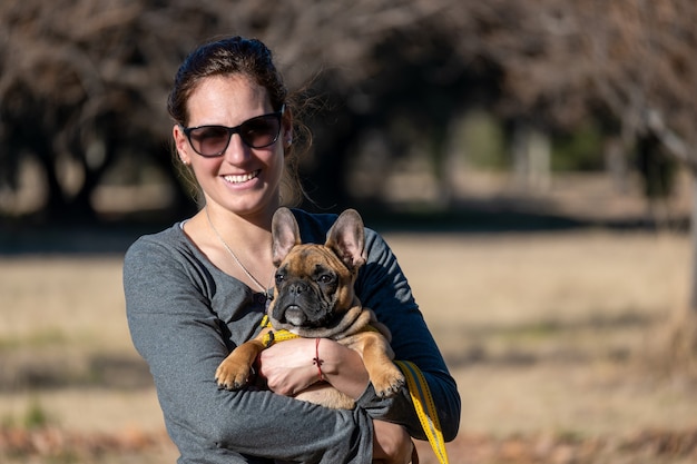 Latijnse vrouw, met Franse buldoghond in park.