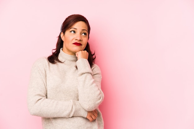 Latijnse vrouw middelbare leeftijd geïsoleerd op roze die verdrietig en peinzend voelt, kijkend naar kopie ruimte.