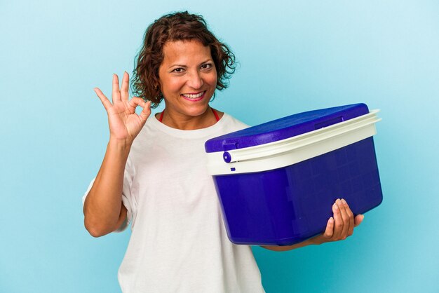 Latijnse vrouw van middelbare leeftijd geïsoleerd op blauwe achtergrond vrolijk en zelfverzekerd weergegeven: ok gebaar.