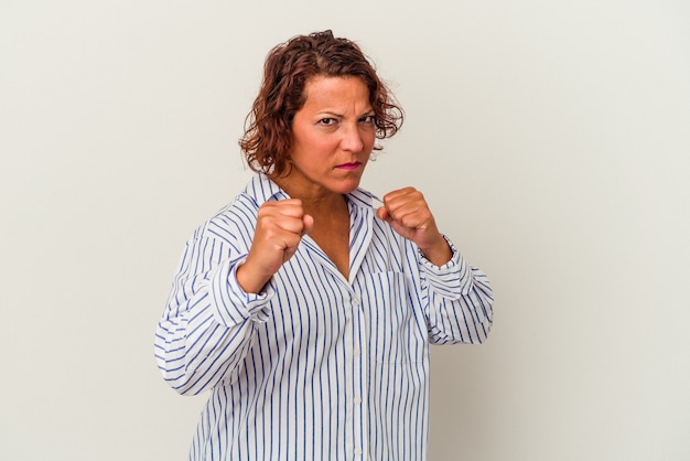 Foto latijnse vrouw van middelbare leeftijd geïsoleerd op een witte achtergrond met vuist naar camera, agressieve gezichtsuitdrukking.