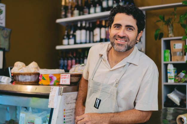 Latijnse winkeleigenaar van middelbare leeftijd die naar de camera kijkt en glimlacht vanaf de plek waar hij aanwezig is Kopieer ruimte