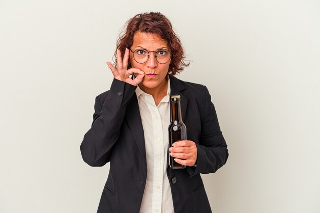 Latijnse zakenvrouw van middelbare leeftijd met een biertje geïsoleerd op een witte achtergrond met vingers op de lippen die een geheim houden.