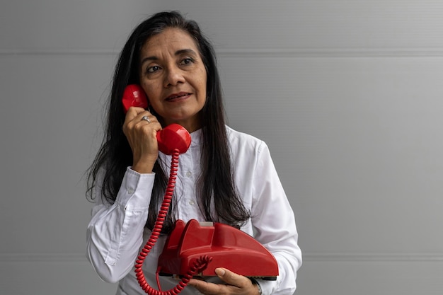 Latin American adult woman with a red headset posing on camera Vintage technology concept