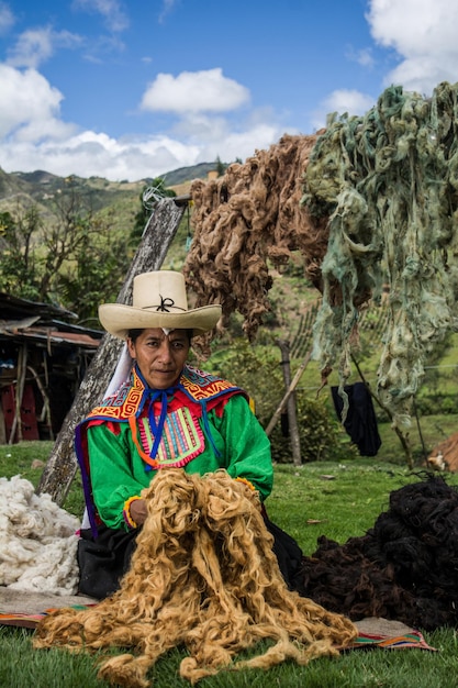 写真 ペルーの腰織りのインカ技法のために着色された羊毛を乾燥させるラテンアメリカのアンデスの母親