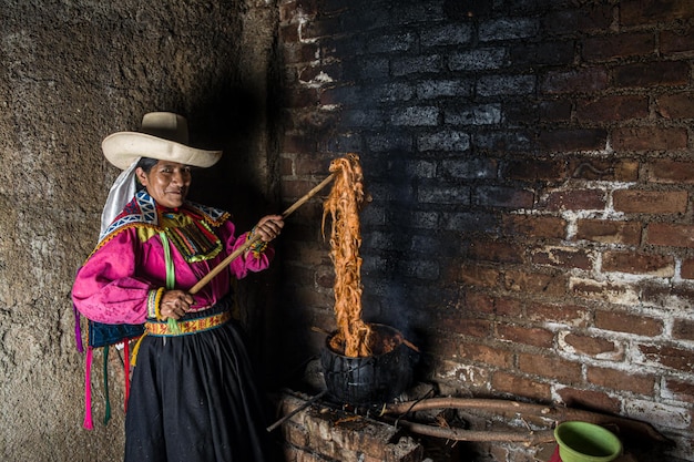 Foto donna andina latinoamericana che tinge la lana di pecora con prodotti naturali ancestrali peruviani