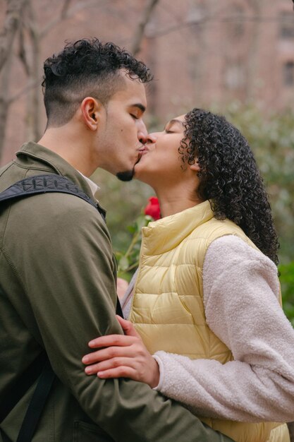 latin American couple kissing near trees in park in kiss day