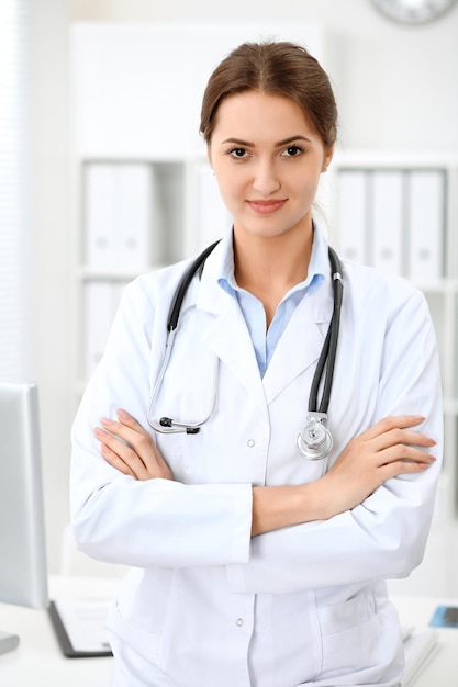 Latin american doctor woman standing with arms crossed and smiling at hospital. Physician ready to examine patient.  Health care, insurance and help concept. Physician ready to examine patient