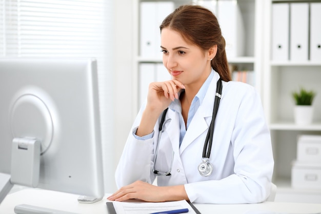 Latin american doctor woman standing with arms crossed and smiling at hospital Physician ready to examine patient