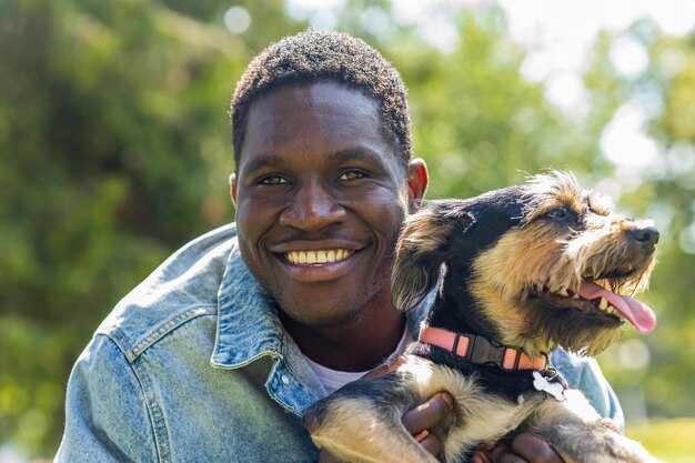 Photo latin american man walking with his cute dog at sunny day in city park lawn on the grass