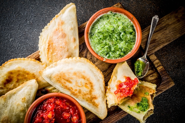 Latin American, mexican, chilean food. Traditional baked pastry empanadas with beef meat, two spicy sauces