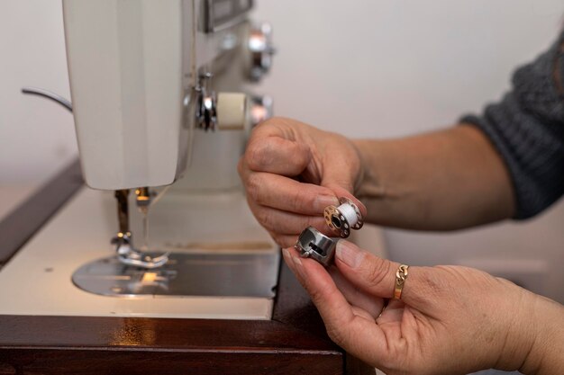 Latin American seamstress holds bobbin of thread from sewing machine