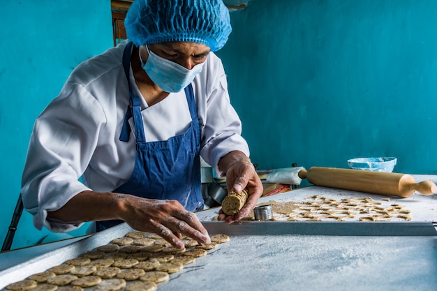 Latin baker preparing the dough and baking colored brioche breads and cookies