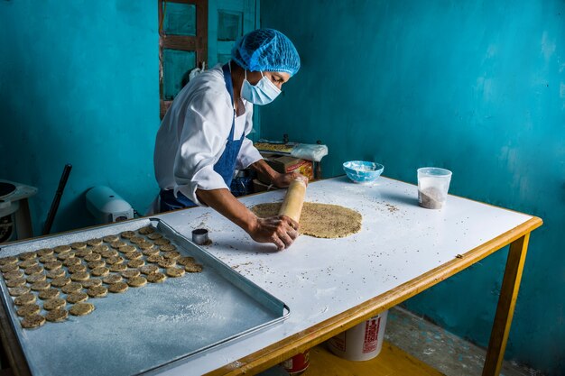 Latin baker preparing the dough and baking colored brioche breads and cookies