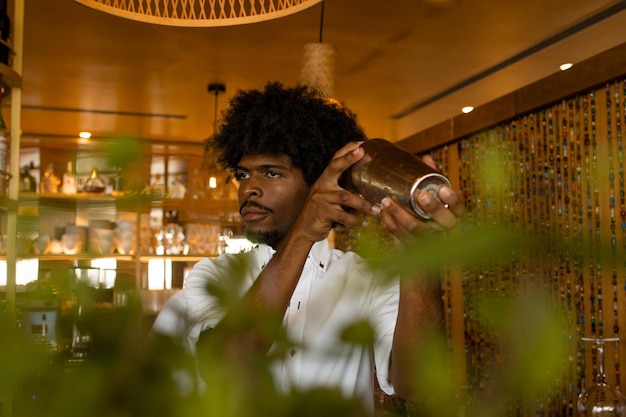 Latin bartender with curly hair mixing a cocktail